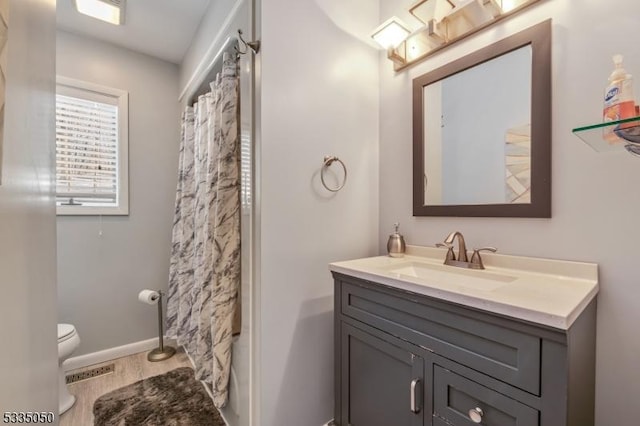 bathroom featuring visible vents, baseboards, vanity, and toilet