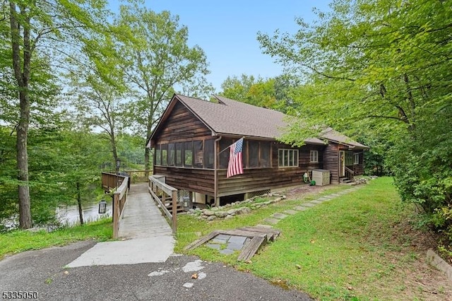 chalet / cabin featuring a sunroom and roof with shingles