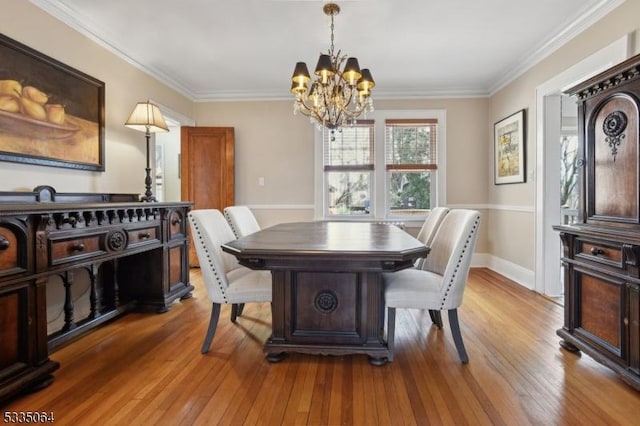 dining space with crown molding, baseboards, light wood-style flooring, and an inviting chandelier