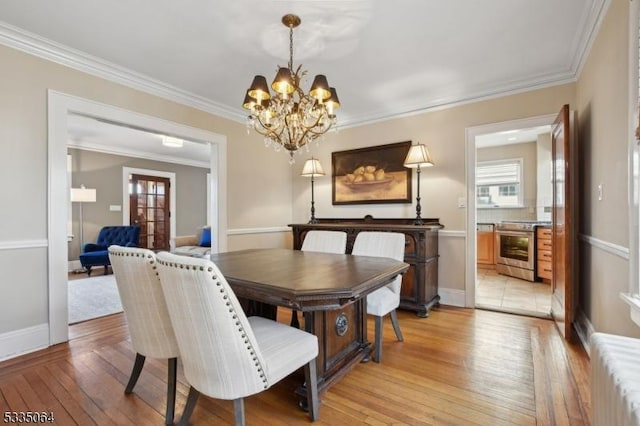 dining space with light wood finished floors, baseboards, ornamental molding, and a chandelier