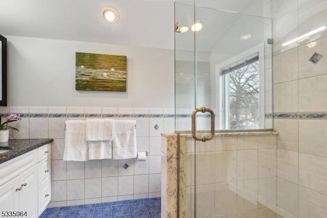 full bathroom with vanity, a shower stall, tile walls, and tile patterned floors