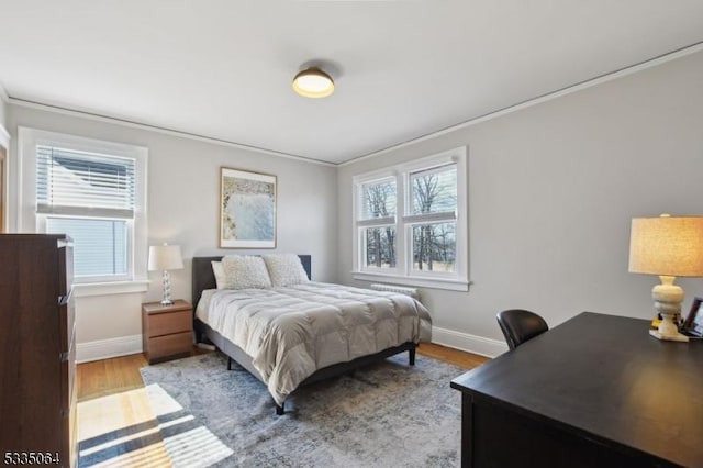 bedroom with multiple windows, baseboards, and wood finished floors