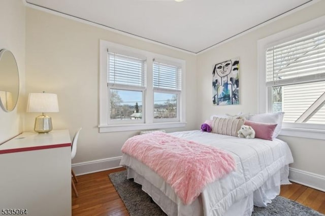 bedroom with multiple windows, wood finished floors, and baseboards