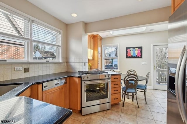 kitchen with appliances with stainless steel finishes, plenty of natural light, decorative backsplash, and light tile patterned floors