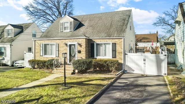 cape cod home featuring a front lawn