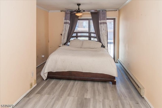 bedroom featuring baseboards, a baseboard heating unit, wood finished floors, and ornamental molding