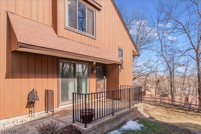 rear view of house with a shingled roof and fence