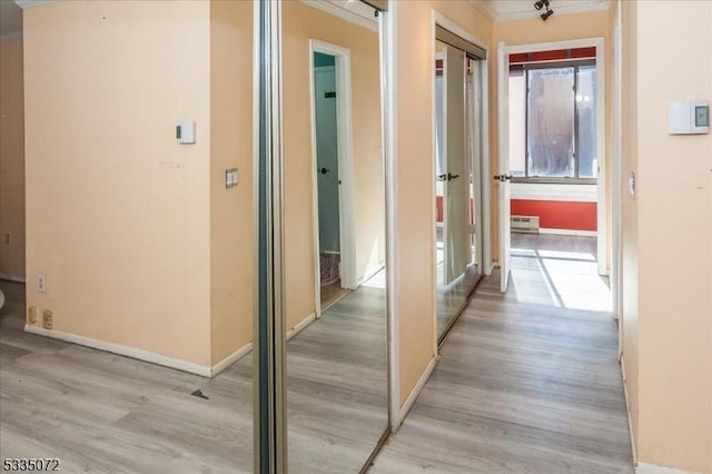 hall with light wood-style floors, a wealth of natural light, and crown molding