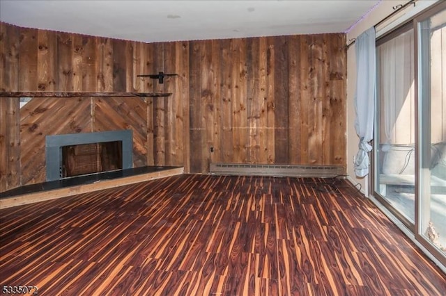 unfurnished living room with baseboard heating, plenty of natural light, and wooden walls