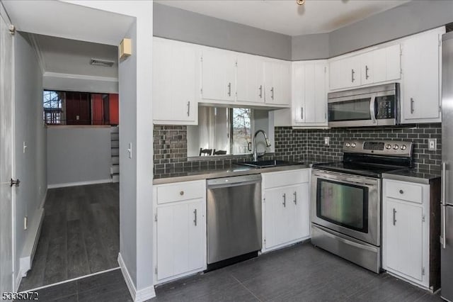 kitchen featuring stainless steel appliances, backsplash, a sink, and white cabinetry