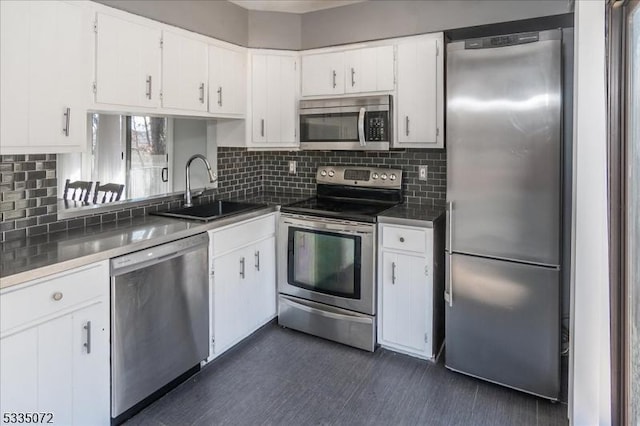 kitchen featuring appliances with stainless steel finishes, white cabinets, a sink, and tasteful backsplash