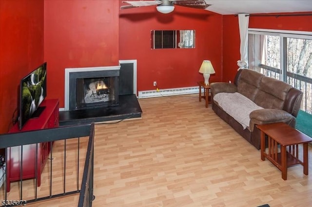 living room featuring a baseboard heating unit, ceiling fan, wood finished floors, and a multi sided fireplace