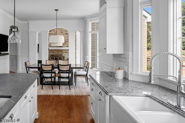 kitchen with hanging light fixtures, sink, white cabinets, and dark stone counters