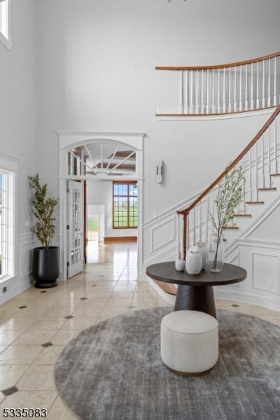 entryway featuring tile patterned flooring, a healthy amount of sunlight, and a towering ceiling