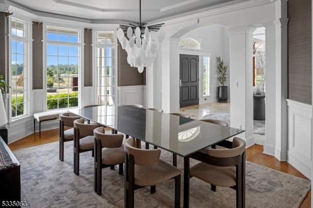 dining area with crown molding, light hardwood / wood-style floors, decorative columns, and a chandelier