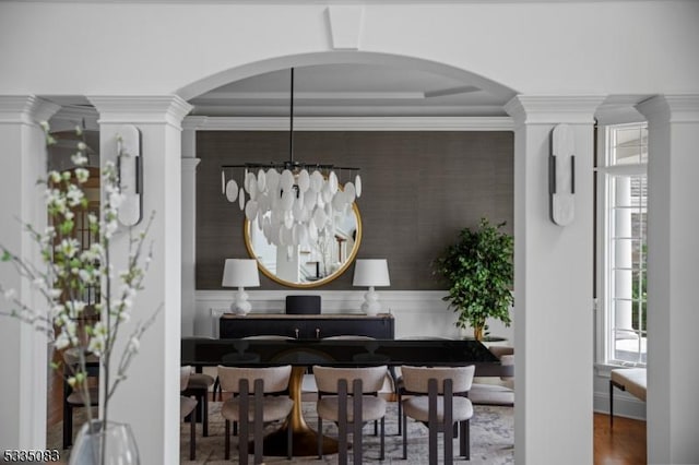 dining space with ornate columns, crown molding, and a chandelier