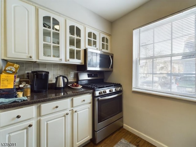 kitchen with white cabinetry, dark stone countertops, stainless steel appliances, tasteful backsplash, and dark hardwood / wood-style flooring