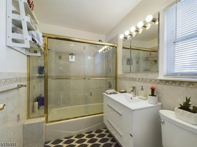 full bathroom with toilet, vanity, shower / bath combination with glass door, and tile walls