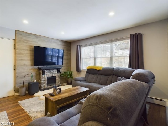 living room featuring dark hardwood / wood-style flooring, a stone fireplace, and a baseboard heating unit