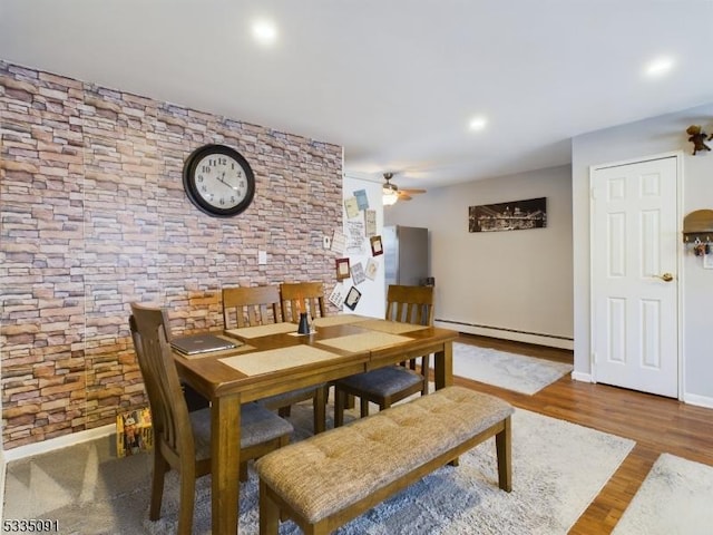 dining area featuring baseboard heating, ceiling fan, and wood-type flooring