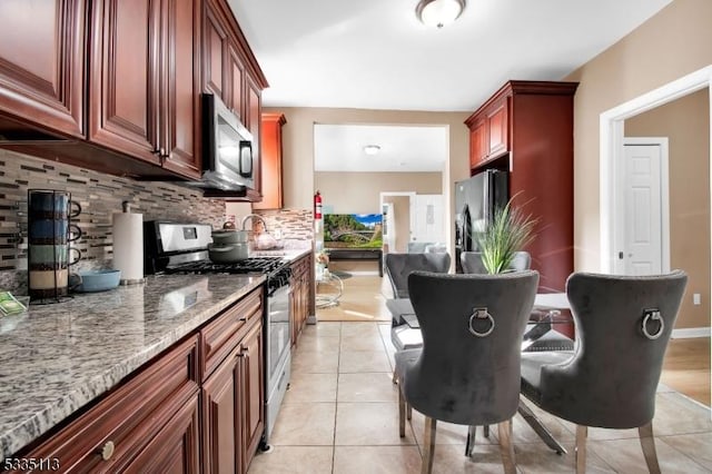 kitchen featuring light stone counters, stainless steel appliances, decorative backsplash, and light tile patterned floors