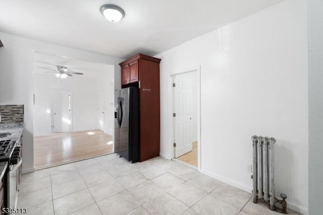 kitchen with radiator, backsplash, light tile patterned floors, ceiling fan, and stainless steel appliances