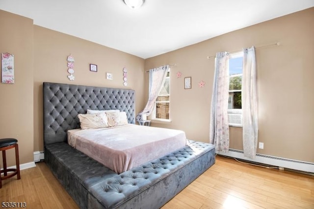 bedroom with light hardwood / wood-style flooring and baseboard heating