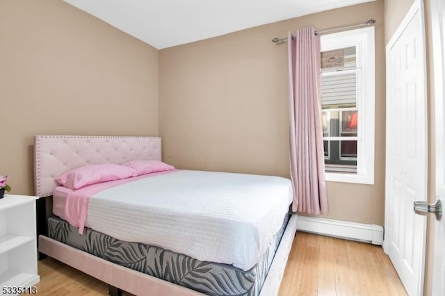 bedroom with a baseboard radiator and light wood-type flooring