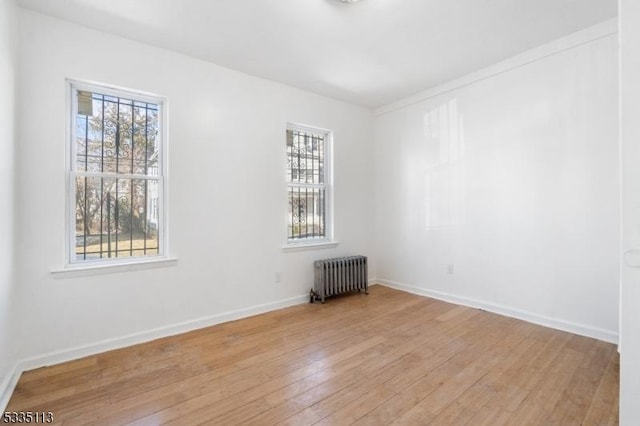 empty room with radiator heating unit and light hardwood / wood-style flooring