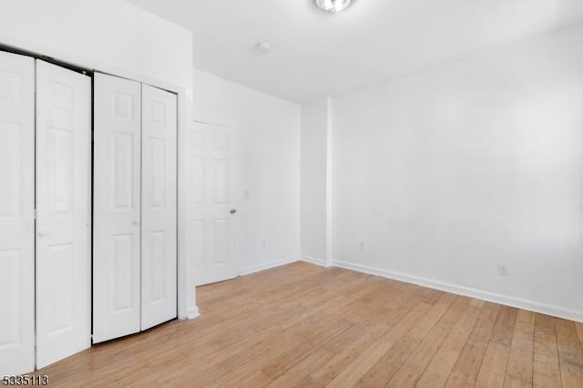 unfurnished bedroom with light wood-type flooring and a closet