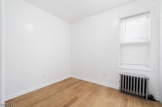 unfurnished room with radiator heating unit and wood-type flooring