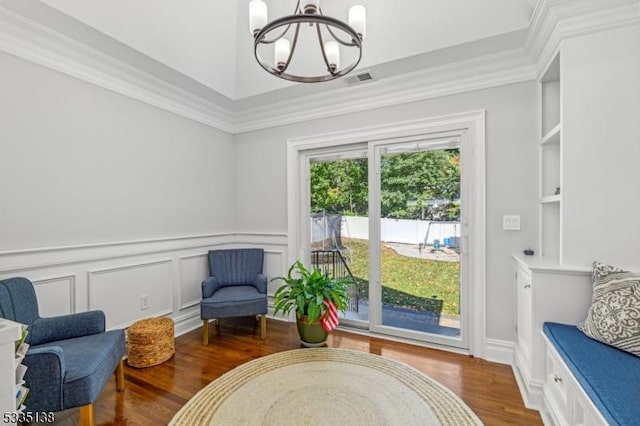 living area featuring ornamental molding, hardwood / wood-style floors, and a chandelier