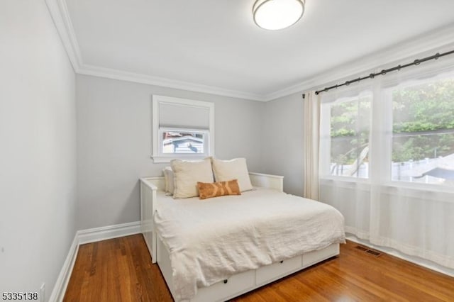 bedroom with crown molding, hardwood / wood-style floors, and multiple windows