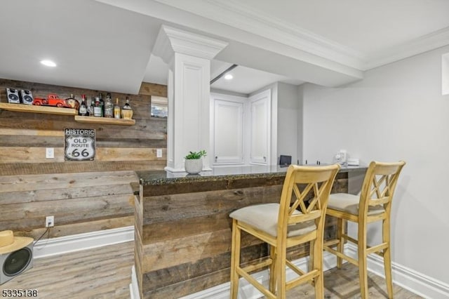 bar with hardwood / wood-style flooring, ornamental molding, and wood walls