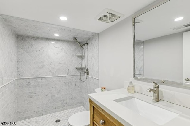 bathroom with vanity, tiled shower, and toilet