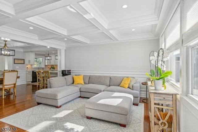 living room with beamed ceiling, crown molding, coffered ceiling, and light hardwood / wood-style flooring