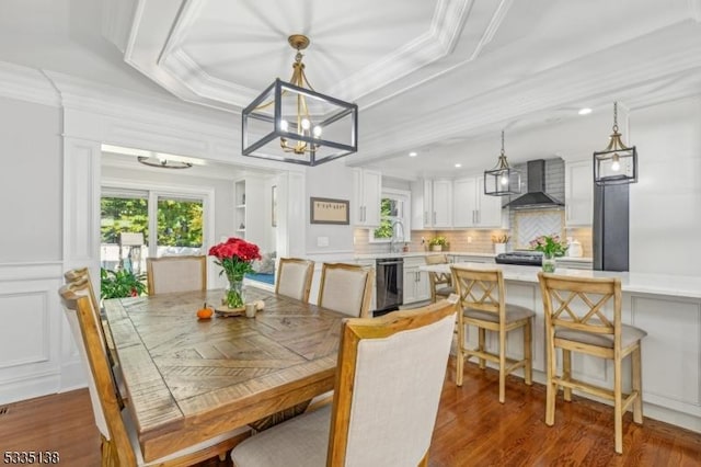 dining space with a tray ceiling, sink, crown molding, and dark hardwood / wood-style flooring