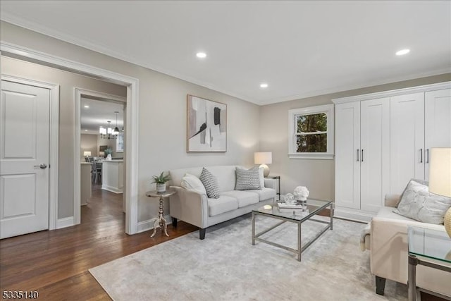 living room featuring dark wood-type flooring, ornamental molding, and a notable chandelier