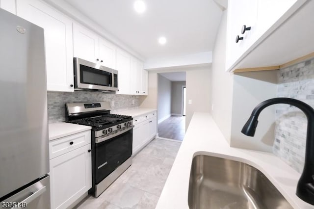 kitchen featuring stainless steel appliances, white cabinetry, sink, and tasteful backsplash