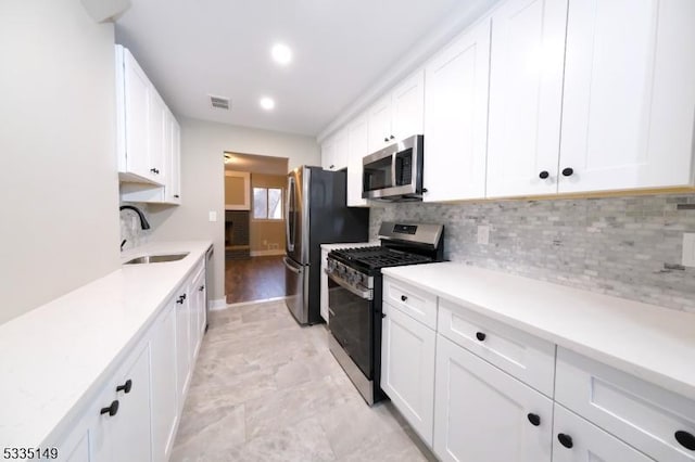 kitchen featuring white cabinetry, appliances with stainless steel finishes, sink, and backsplash