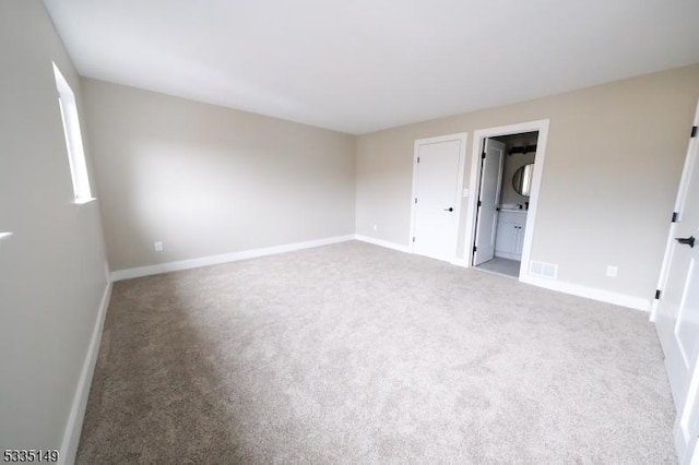 unfurnished bedroom with ensuite bath and carpet flooring