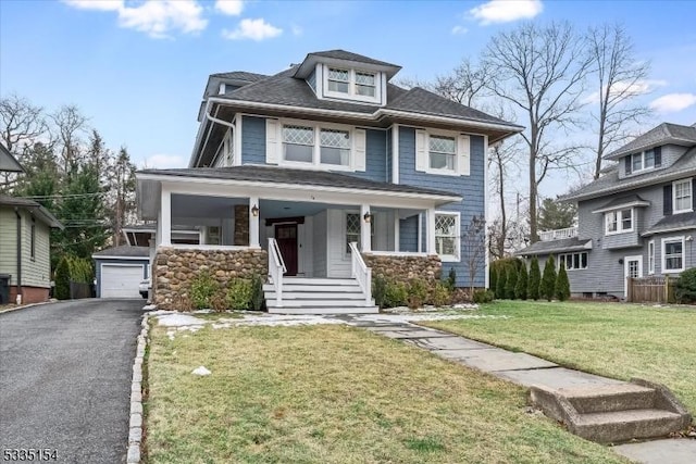 american foursquare style home featuring an outbuilding, a front lawn, a porch, and a detached garage