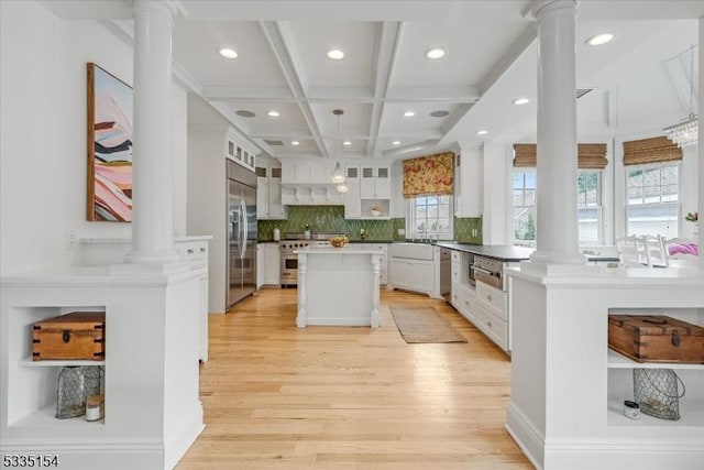 kitchen featuring decorative columns, glass insert cabinets, appliances with stainless steel finishes, white cabinets, and a kitchen island