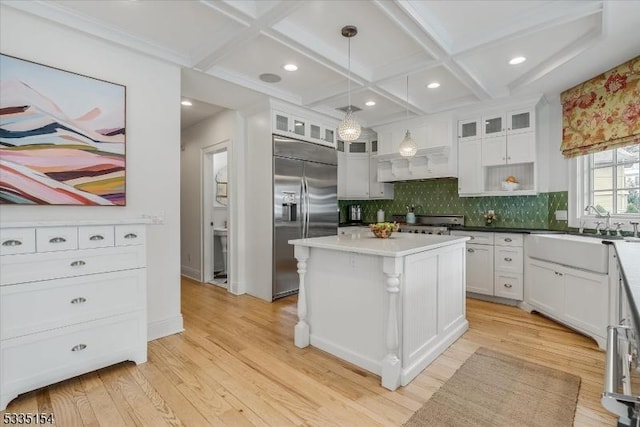 kitchen with decorative light fixtures, light countertops, white cabinetry, a sink, and built in refrigerator