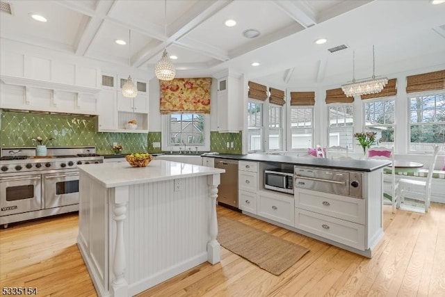 kitchen with white cabinetry, a kitchen island, appliances with stainless steel finishes, and decorative light fixtures