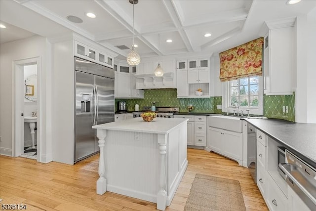 kitchen featuring a center island, hanging light fixtures, appliances with stainless steel finishes, glass insert cabinets, and white cabinets