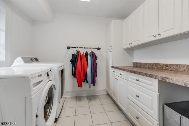 laundry room featuring baseboards, cabinet space, washing machine and clothes dryer, and light tile patterned floors