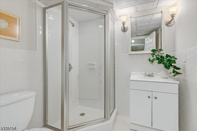 full bathroom featuring toilet, vanity, tile walls, wainscoting, and a shower stall