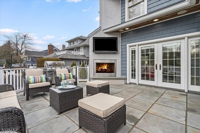 view of patio with french doors and an outdoor living space with a fireplace