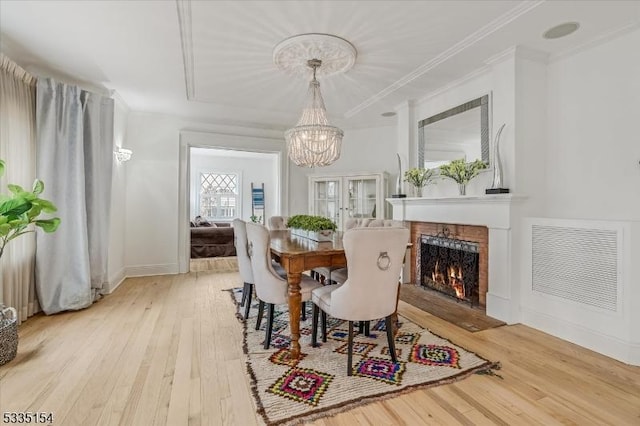 dining area with a chandelier, ornamental molding, light wood-type flooring, and visible vents